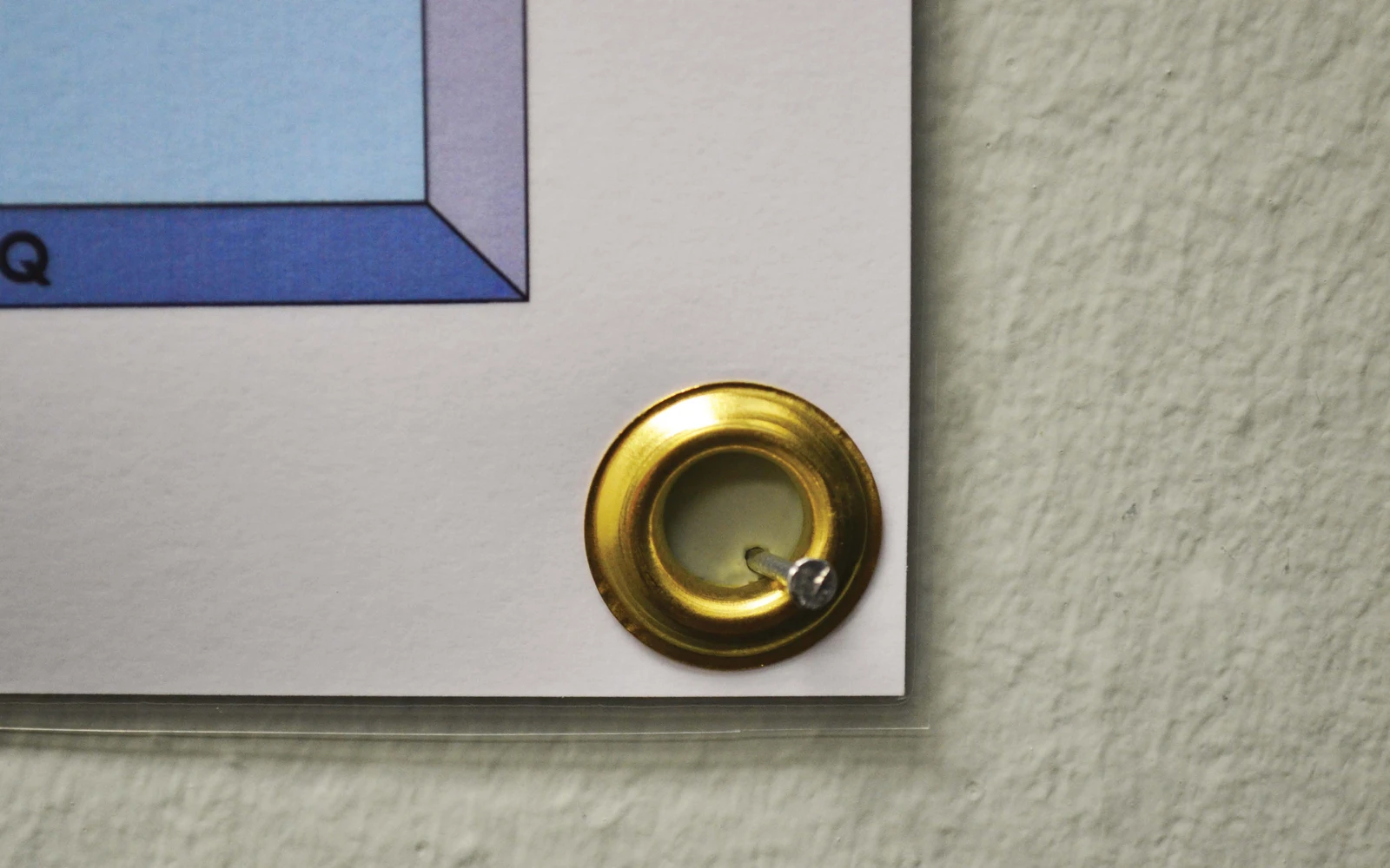 A brass grommet set into the corner of a laminated map, screwed to the wall