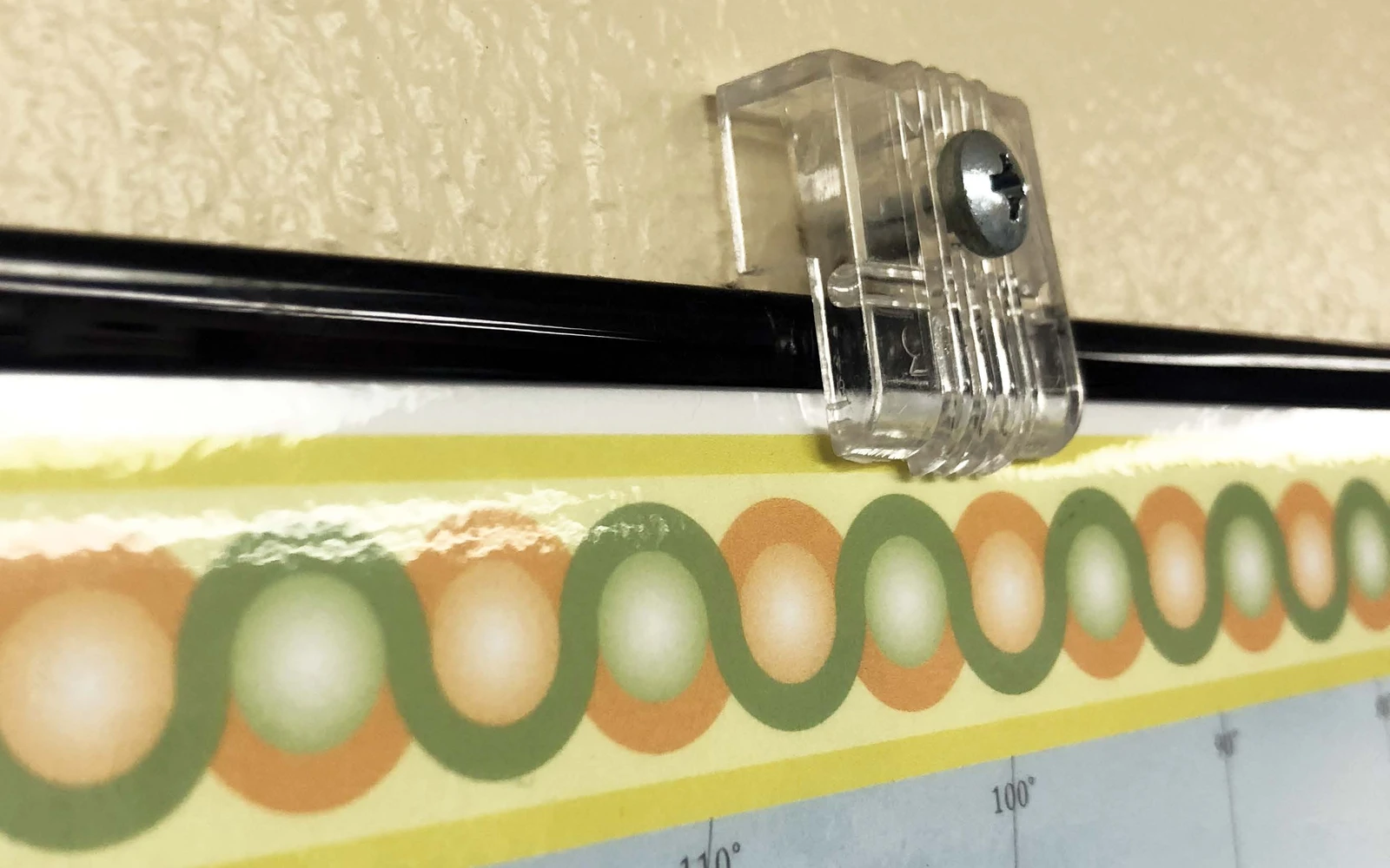 A clear mirror holder gripping the bottom edge of a framed mounted map
