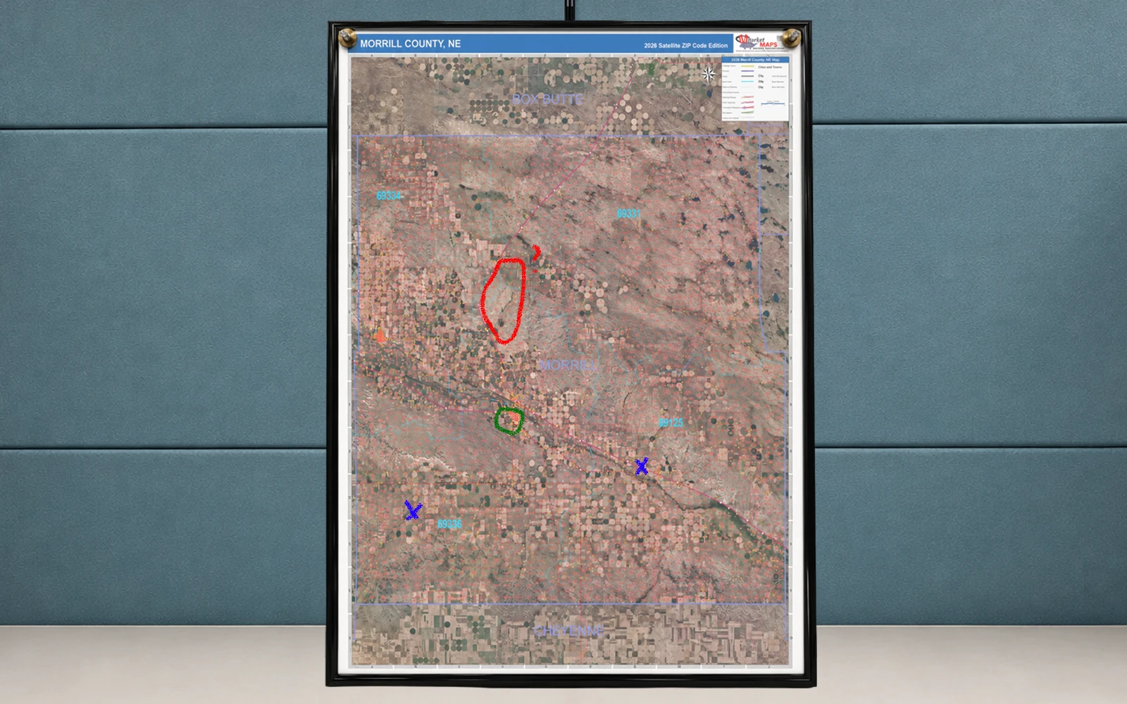 A framed aerial county map marked up in red and blue