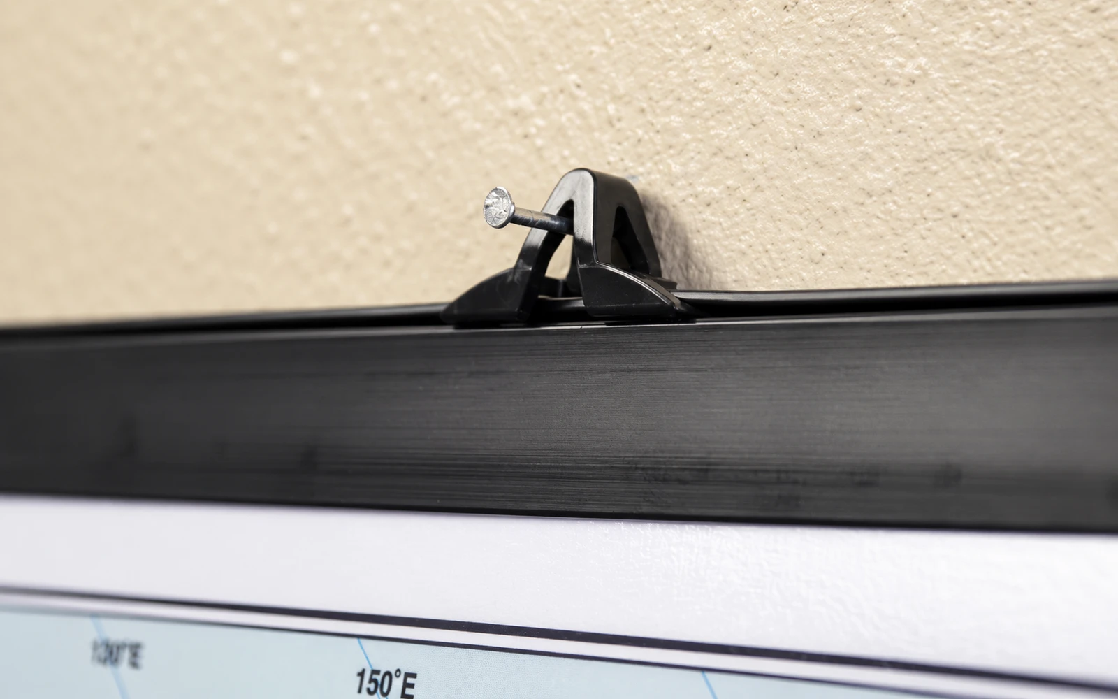 A wall map hanging from a black plastic rail fixed to the wall