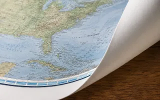 The corner of an unmounted paper map, curling gently away from the wall