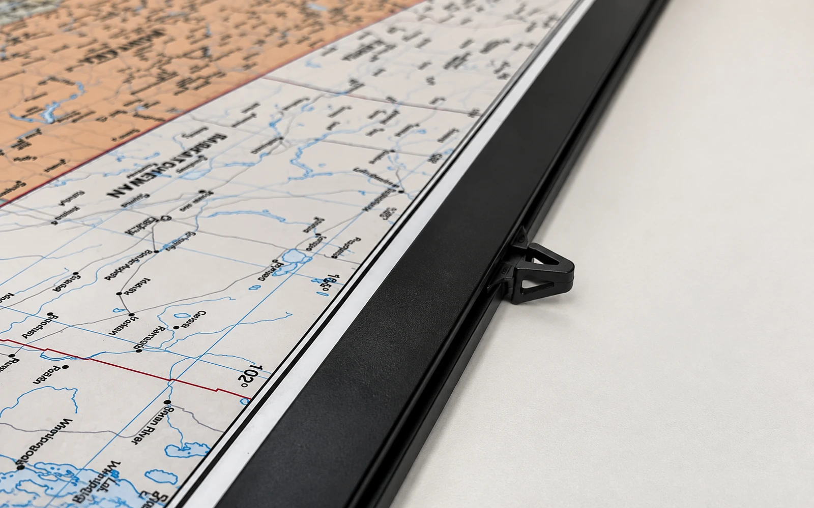 Close-up of a black plastic rail fitted along the edge of a wall map