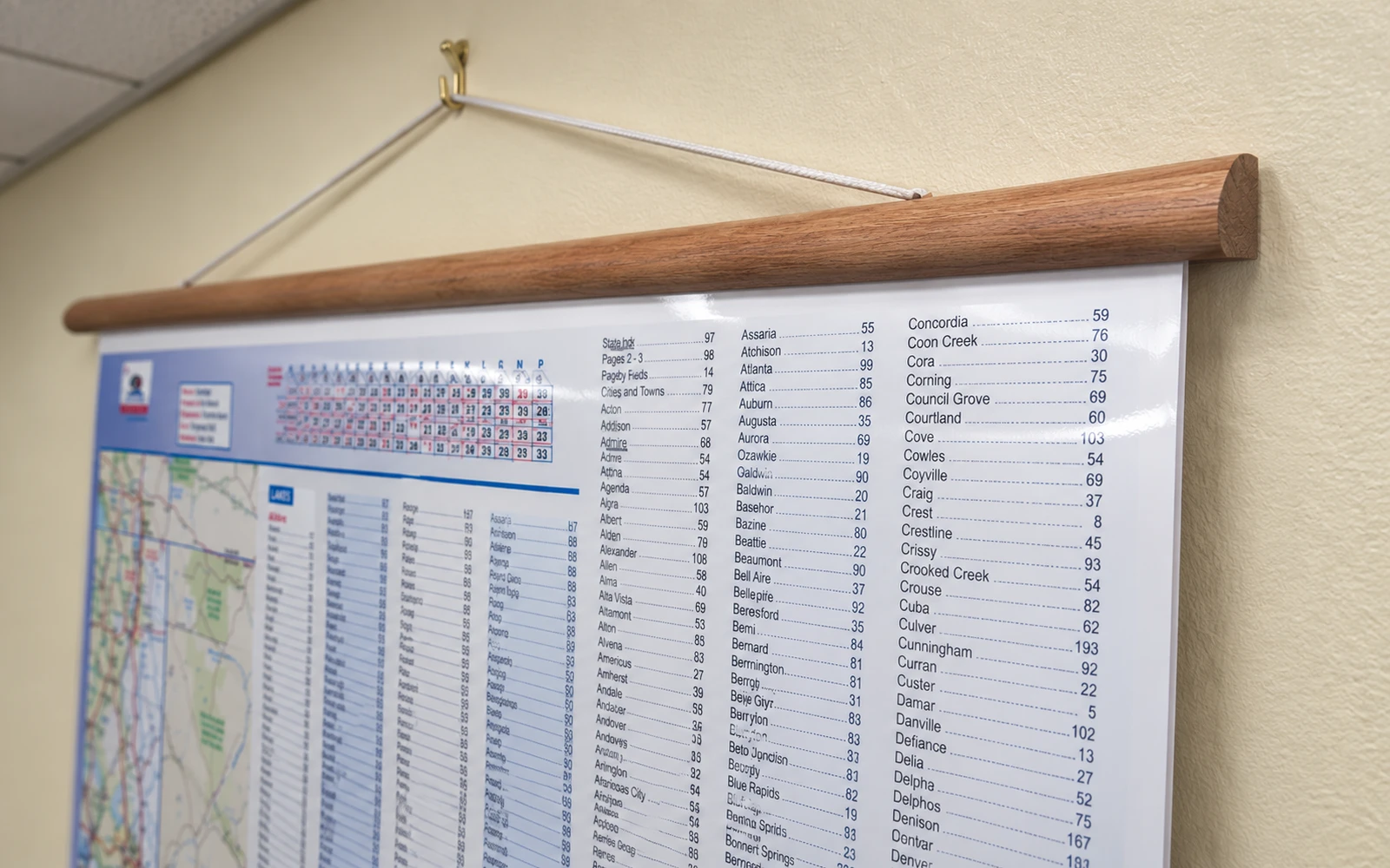 A wall map hanging from a cherry-stained wooden rail and a cord